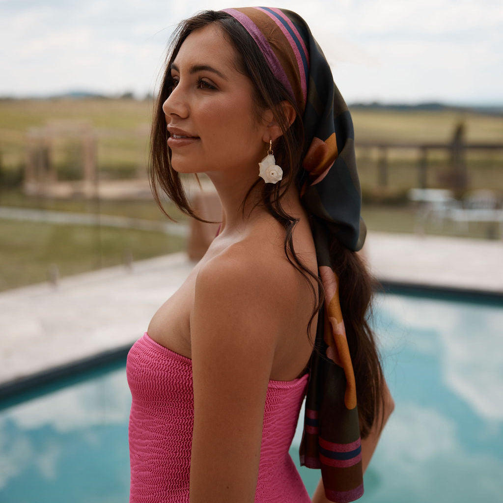 Tropical silk sarong worn as a head scarf in dark khaki, bright pink and copper tones, on a woman in pink bathing suit.