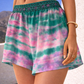 Rosa Paloma pink and aqua tie-dye silk shorts on model, lightweight resortwear photographed outdoors.