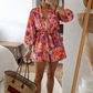Person wearing a colorful floral kimono holding a straw bag indoors.